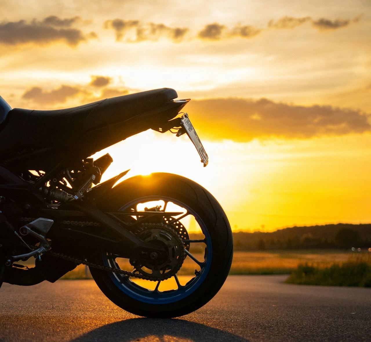 Motorcycle parked on a road at sunset